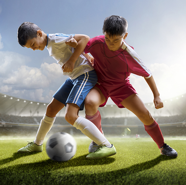 Childrens are playing soccer on grand arena in sunlights